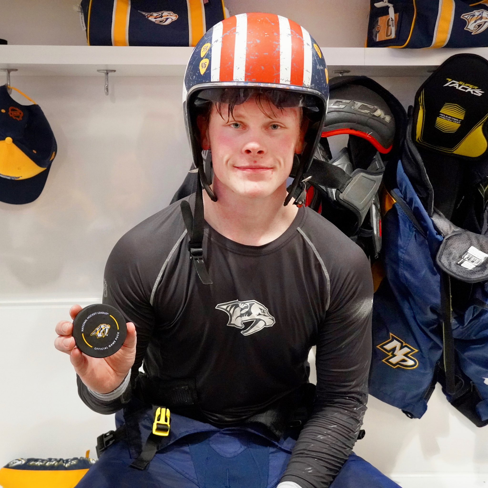 Juuso Parssinen holds up his game puck from his first NHL goal with a helmet on and a smile